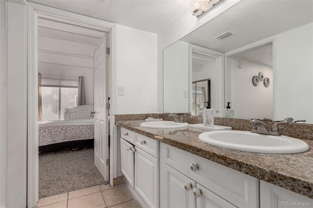 ensuite bathroom featuring a sink, visible vents, double vanity, and tile patterned flooring