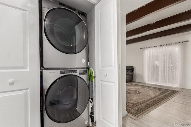 clothes washing area featuring stacked washer / dryer, laundry area, and wood finished floors