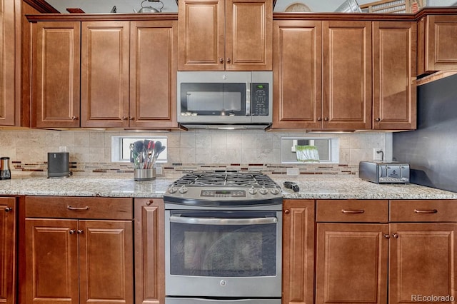 6132 Cubbage Dr, Colorado Springs, CO 80924 - kitchen with backsplash, brown cabinetry, stainless steel appliances, and light stone counters