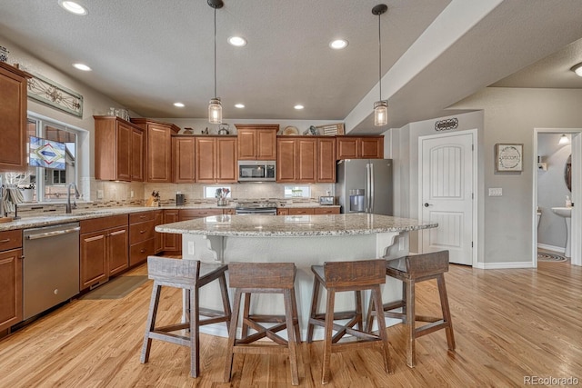 6132 Cubbage Dr, Colorado Springs, CO 80924 - kitchen with light wood-type flooring, brown cabinetry, a breakfast bar area, and appliances with stainless steel finishes