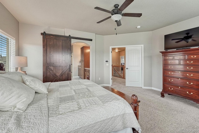 6132 Cubbage Dr, Colorado Springs, CO 80924 - carpeted bedroom featuring ensuite bathroom, baseboards, ceiling fan, arched walkways, and a barn door