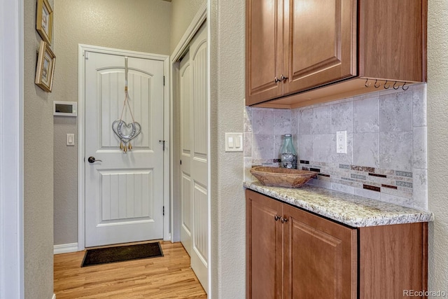 6132 Cubbage Dr, Colorado Springs, CO 80924 - kitchen with brown cabinetry, light wood-style flooring, and backsplash