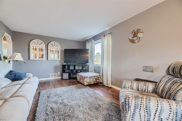 living area with visible vents, baseboards, and wood finished floors