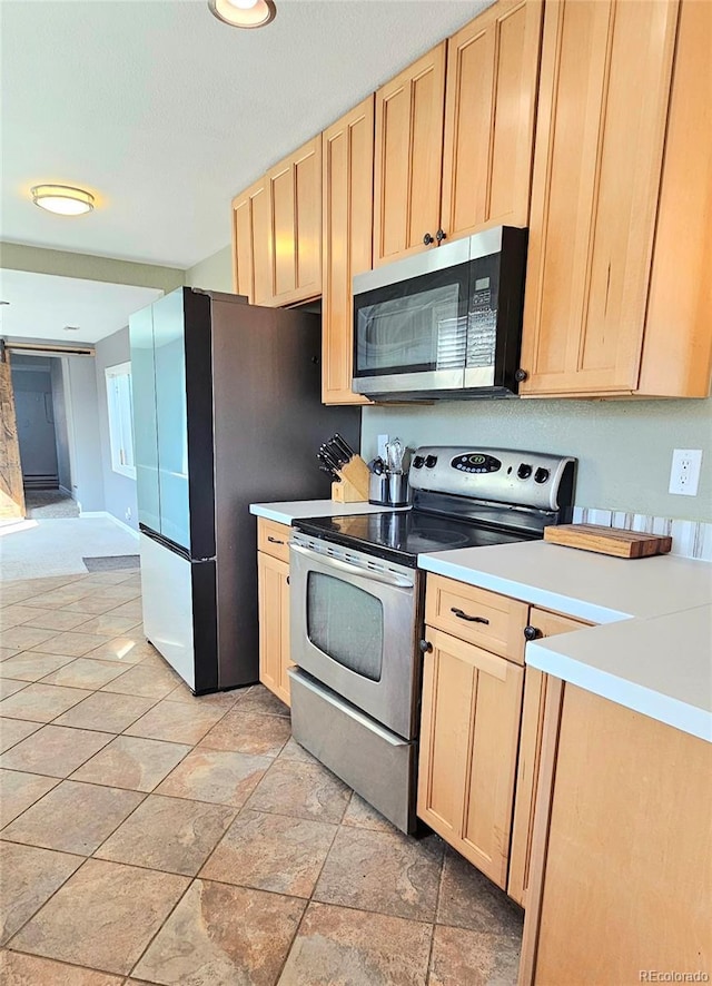 kitchen with light countertops, appliances with stainless steel finishes, and light brown cabinetry