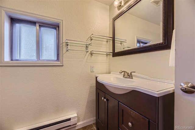 bathroom with visible vents, vanity, a textured wall, and a baseboard radiator