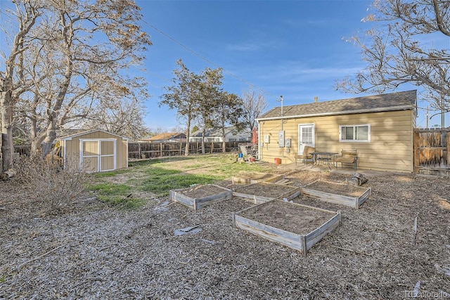 view of yard with an outdoor structure, a garden, a storage unit, and a fenced backyard