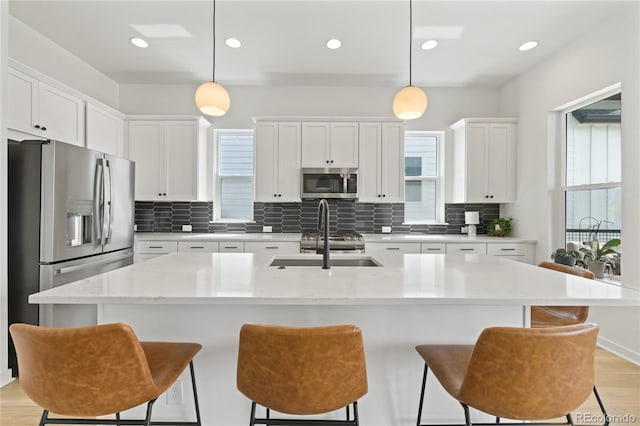 16722 Shoshone St, Broomfield, CO 80023 - kitchen featuring appliances with stainless steel finishes, a sink, decorative backsplash, a kitchen bar, and recessed lighting