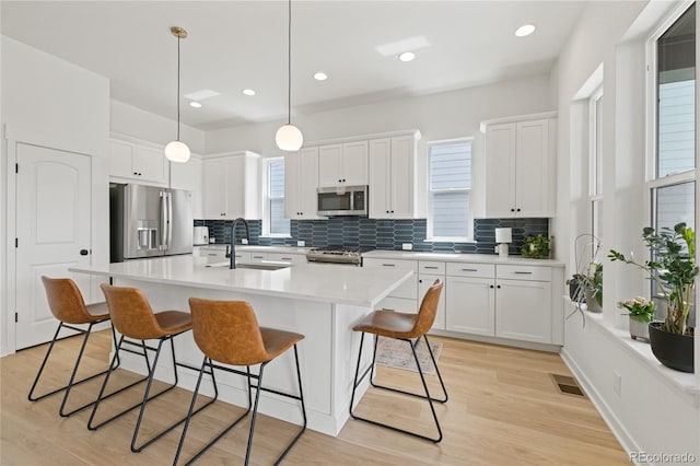 16722 Shoshone St, Broomfield, CO 80023 - kitchen featuring stainless steel appliances, decorative backsplash, a kitchen bar, white cabinetry, and recessed lighting