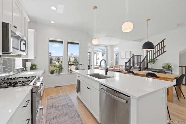 16722 Shoshone St, Broomfield, CO 80023 - kitchen featuring appliances with stainless steel finishes, a sink, backsplash, light wood-style flooring, and white cabinets