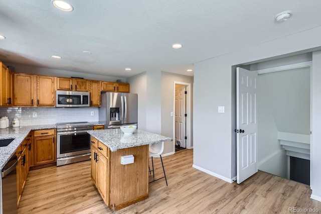 4620 E 135th Way, Thornton, CO 80241 - kitchen with appliances with stainless steel finishes, light wood-style floors, a center island, a breakfast bar, and light stone countertops
