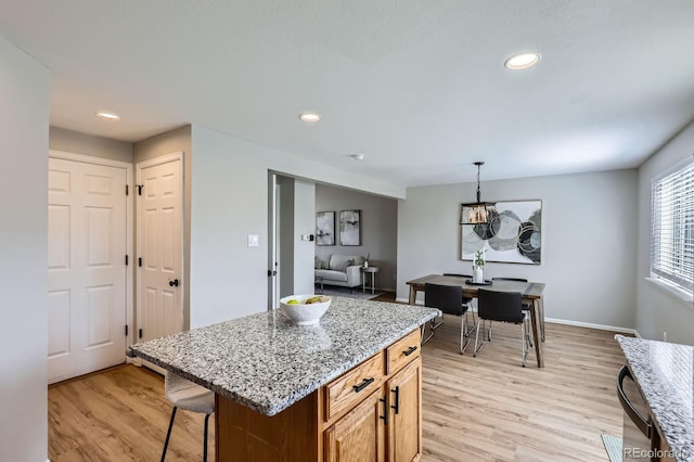 4620 E 135th Way, Thornton, CO 80241 - kitchen featuring light wood-type flooring, recessed lighting, light stone counters, a kitchen breakfast bar, and a center island