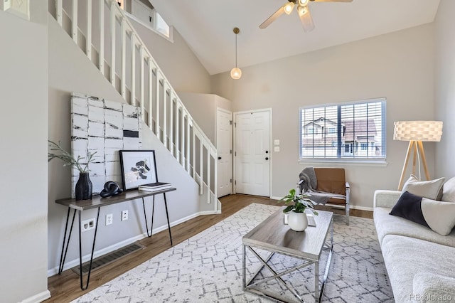 4620 E 135th Way, Thornton, CO 80241 - living area featuring stairs, wood finished floors, a ceiling fan, baseboards, and high vaulted ceiling