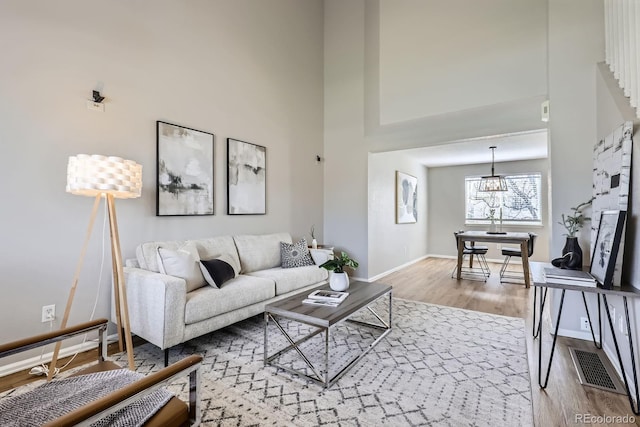 4620 E 135th Way, Thornton, CO 80241 - living area featuring wood finished floors, baseboards, a chandelier, and a high ceiling