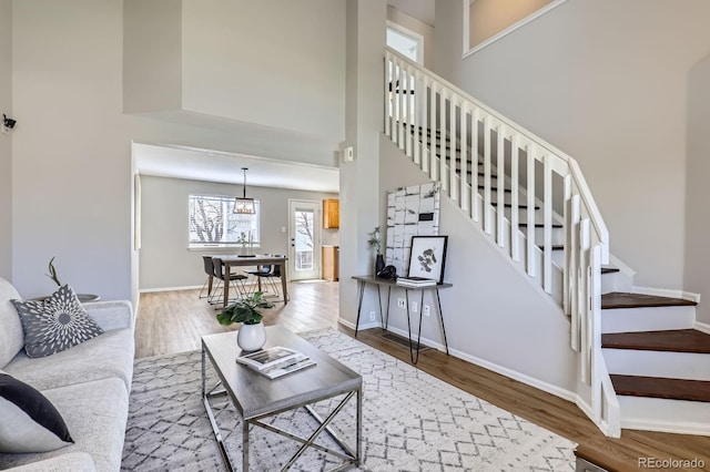 4620 E 135th Way, Thornton, CO 80241 - living room featuring stairs, wood finished floors, a towering ceiling, and baseboards