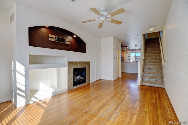 unfurnished living room with a fireplace, light hardwood / wood-style flooring, and ceiling fan