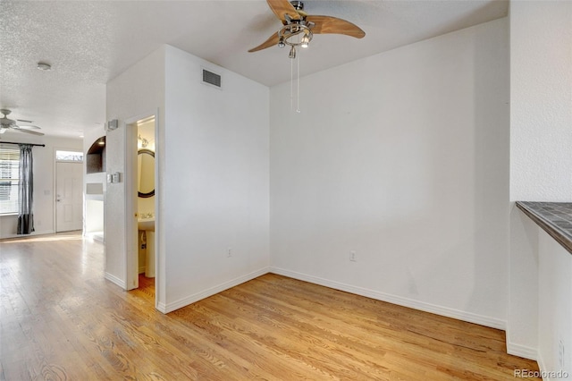 unfurnished room with ceiling fan, a textured ceiling, and light wood-type flooring