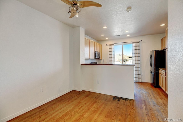 kitchen with ceiling fan, black refrigerator, light wood-type flooring, kitchen peninsula, and light brown cabinets