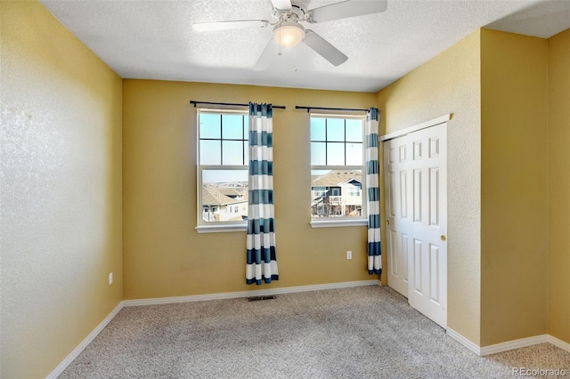 empty room with ceiling fan, light carpet, and a textured ceiling