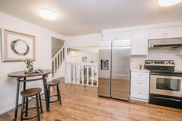 kitchen featuring under cabinet range hood, white cabinets, light wood-type flooring, and appliances with stainless steel finishes