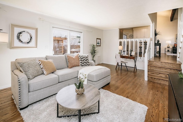 living room featuring baseboards, wood finished floors, and stairs