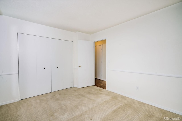 unfurnished bedroom with carpet flooring, baseboards, and a closet