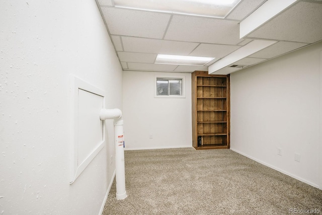 finished below grade area with a drop ceiling, baseboards, and carpet floors