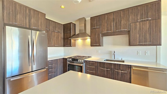 kitchen featuring wall chimney exhaust hood, appliances with stainless steel finishes, sink, and decorative backsplash