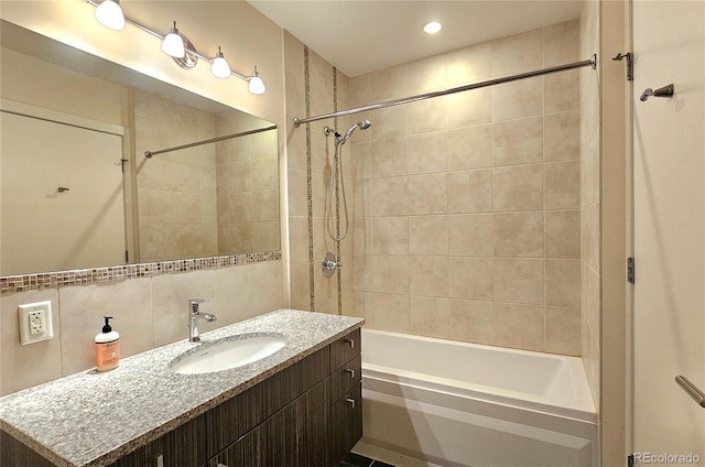 bathroom with vanity, tiled shower / bath combo, and decorative backsplash