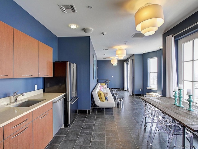 kitchen with sink, stainless steel dishwasher, and dark tile patterned floors