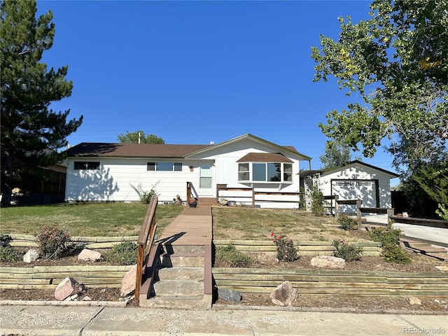 view of front of property featuring a front lawn, an outbuilding, and a garage