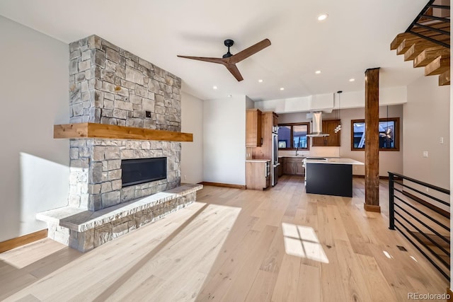 living room featuring a fireplace, light hardwood / wood-style floors, and ceiling fan