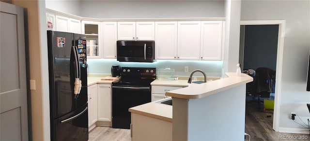 7355 S Alkire St Unit 203, Littleton, CO 80127 - kitchen with black appliances, light wood-type flooring, a peninsula, white cabinetry, and light countertops