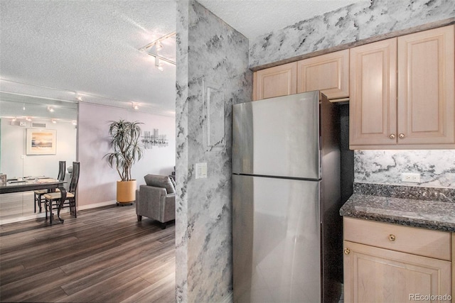 kitchen featuring dark hardwood / wood-style floors, light brown cabinetry, a textured ceiling, and stainless steel refrigerator