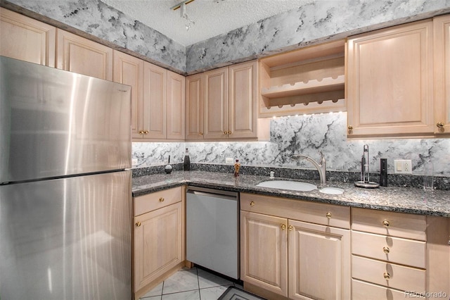 kitchen featuring a textured ceiling, stainless steel appliances, dark stone counters, and sink