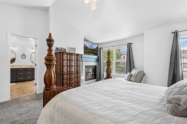 5944 S Yank Ct, Littleton, CO 80127 - bedroom with lofted ceiling, a glass covered fireplace, light colored carpet, ensuite bath, and ceiling fan
