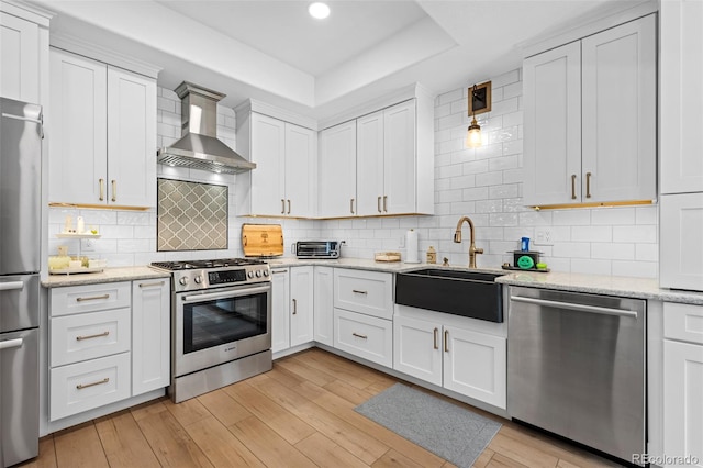 5944 S Yank Ct, Littleton, CO 80127 - kitchen with appliances with stainless steel finishes, wall chimney range hood, a sink, a raised ceiling, and white cabinets