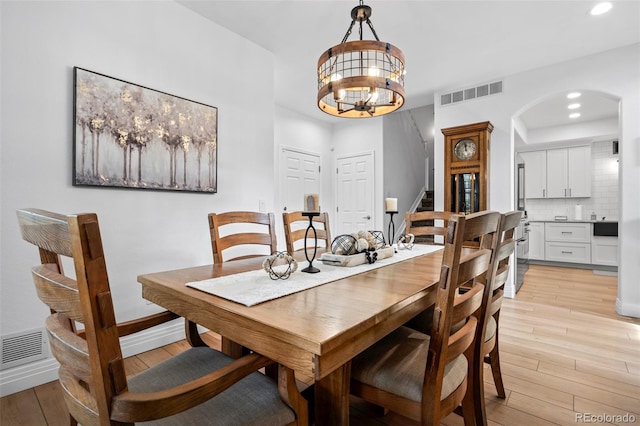 5944 S Yank Ct, Littleton, CO 80127 - dining room featuring arched walkways, light wood-style floors, recessed lighting, a chandelier, and stairway