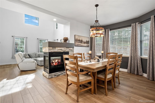 5944 S Yank Ct, Littleton, CO 80127 - dining area with a stone fireplace, a chandelier, light wood-style floors, and plenty of natural light