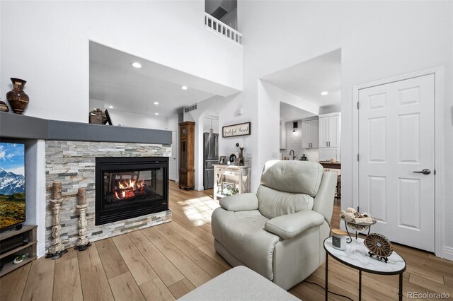 5944 S Yank Ct, Littleton, CO 80127 - living room with light wood-style floors, a stone fireplace, a high ceiling, arched walkways, and recessed lighting