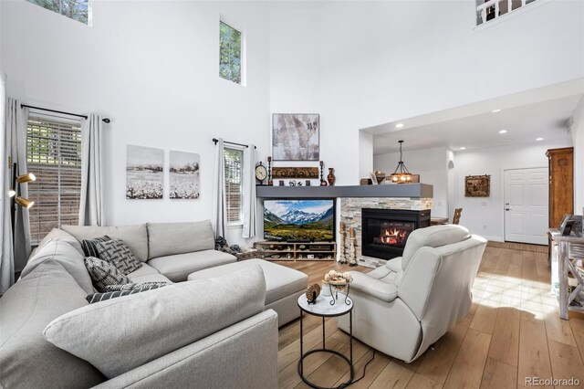 5944 S Yank Ct, Littleton, CO 80127 - living area with a towering ceiling, a stone fireplace, light wood-style flooring, recessed lighting, and baseboards