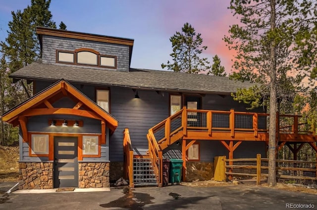 142 High Point Dr, Breckenridge, CO 80424 - view of front facade featuring stone siding, a wooden deck, stairway, a shingled roof, and fence