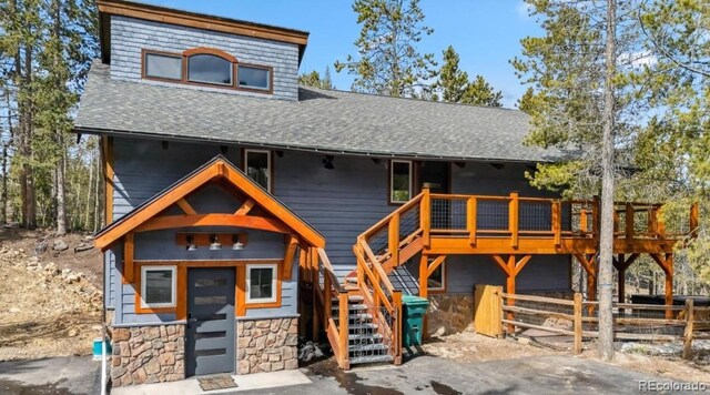 142 High Point Dr, Breckenridge, CO 80424 - view of front of house with a shingled roof, stairs, a deck, fence, and stone siding