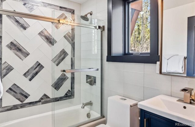142 High Point Dr, Breckenridge, CO 80424 - bathroom with tile walls, combined bath / shower with glass door, vanity, tasteful backsplash, and toilet