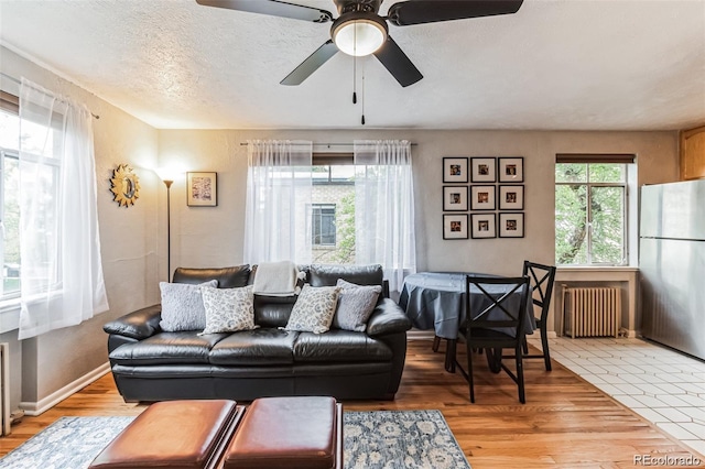 living room featuring hardwood / wood-style flooring, ceiling fan, radiator, and a textured ceiling