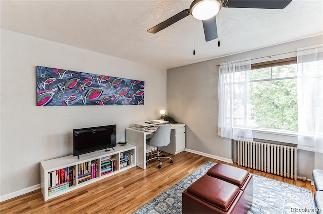 office area featuring radiator, wood-type flooring, a textured ceiling, and ceiling fan