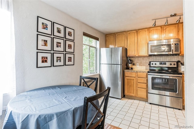 kitchen with rail lighting, appliances with stainless steel finishes, and backsplash