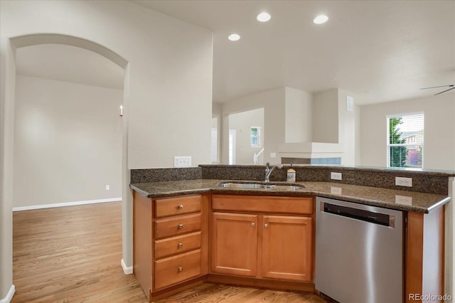 kitchen with ceiling fan, dishwasher, sink, light hardwood / wood-style floors, and dark stone counters