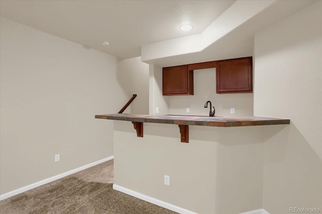 kitchen featuring carpet, a breakfast bar, kitchen peninsula, and sink