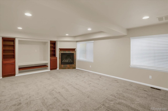 unfurnished living room with built in shelves, a fireplace, and light colored carpet