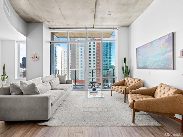 living area with a wealth of natural light, a view of city, floor to ceiling windows, and wood finished floors